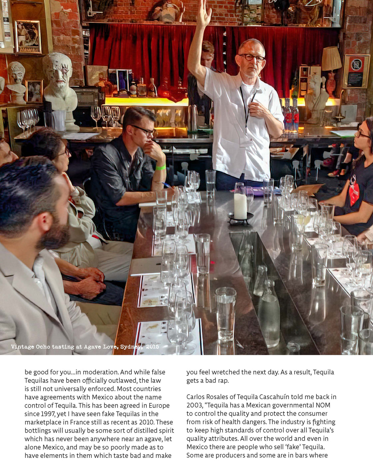 Group of people in a bar setting with a person standing and gesturing.